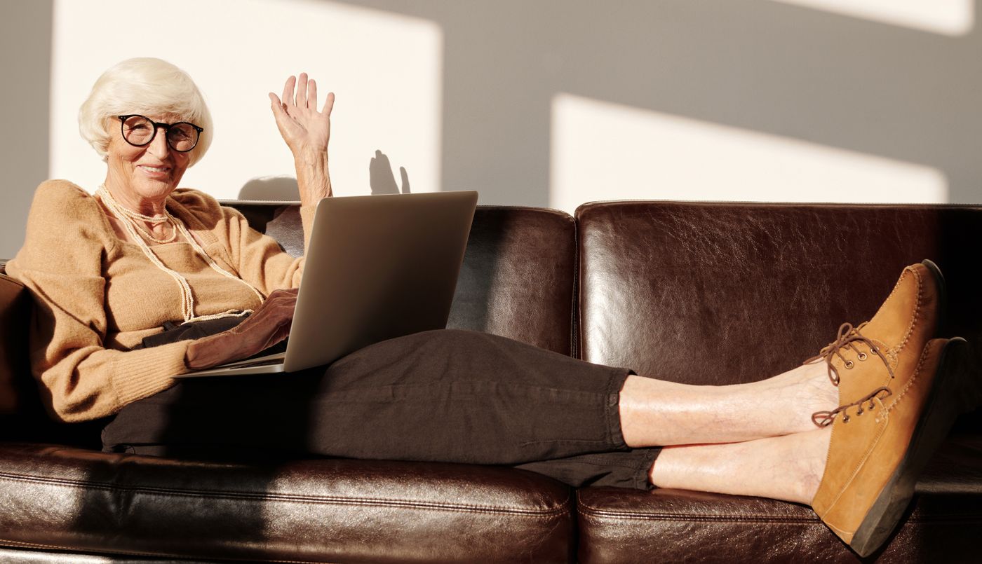 Confident older resident smiling with a laptop in her sunlit living room